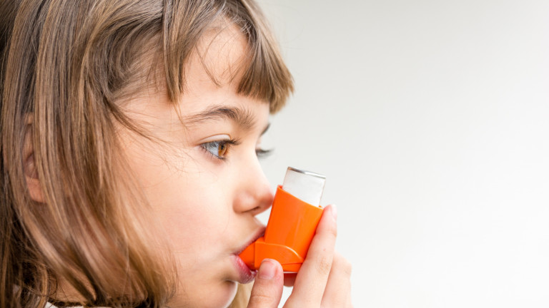 Young girl using asthma inhaler